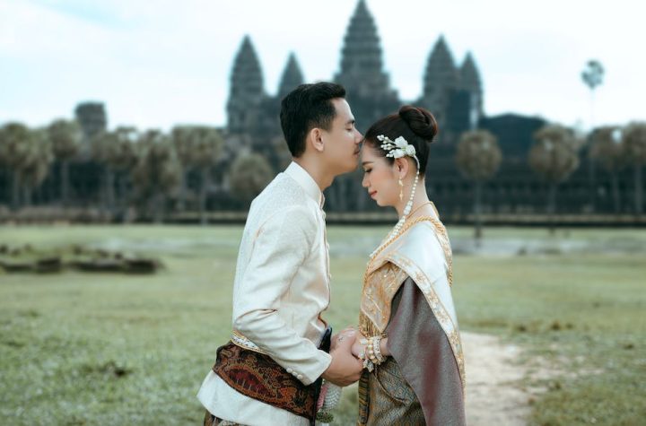 a-couple-in-traditional-clothing-standing-in-front-of-a-temple